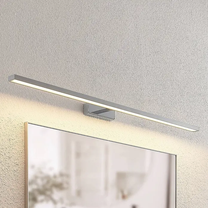 Lindby Wandleuchte Jukka - chrom / silber - Silberne, lineare LED-Spiegelleuchte über einem Spiegel montiert.