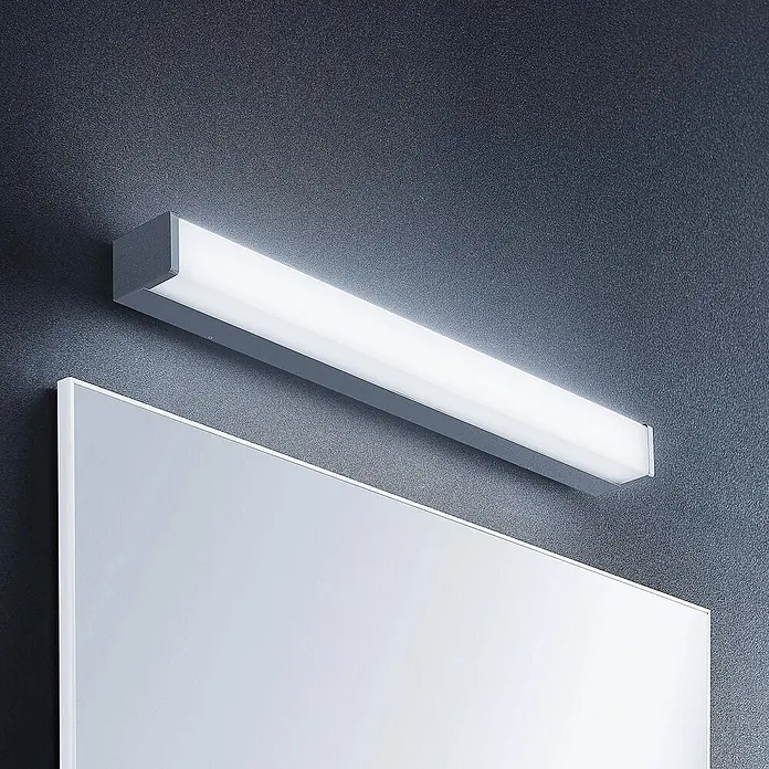 Lindby Wandleuchte Klea - L x B x H: 7 x 60 x 5 cm, chrom / silber - Lineare LED-Spiegelleuchte mit grauem Gehäuse und weißem Diffusor, über einem Spiegel montiert.
