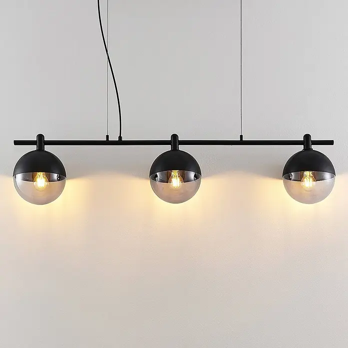 Lucande Pendelleuchte Dustian - klar, Schwarz, E27 - Schwarze Metall-Pendelleuchte mit drei kugelförmigen Schirmen, halb schwarz, halb Rauchglas, mit leuchtenden Glühbirnen.