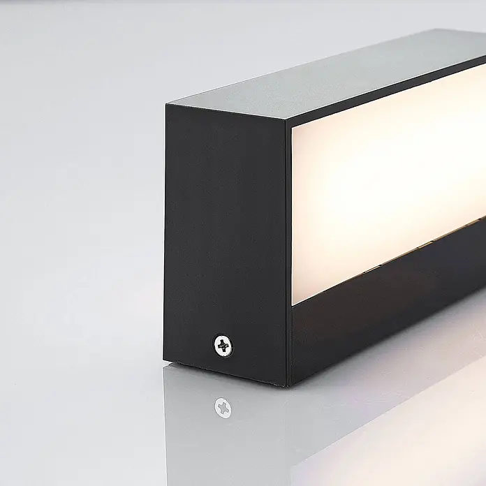 Lindby Außenwandleuchte Nienke - schwarz, schwarz, IP65 - Schwarze rechteckige Wandleuchte mit warmweißem Licht. Eine Schraube ist an der Seite sichtbar.