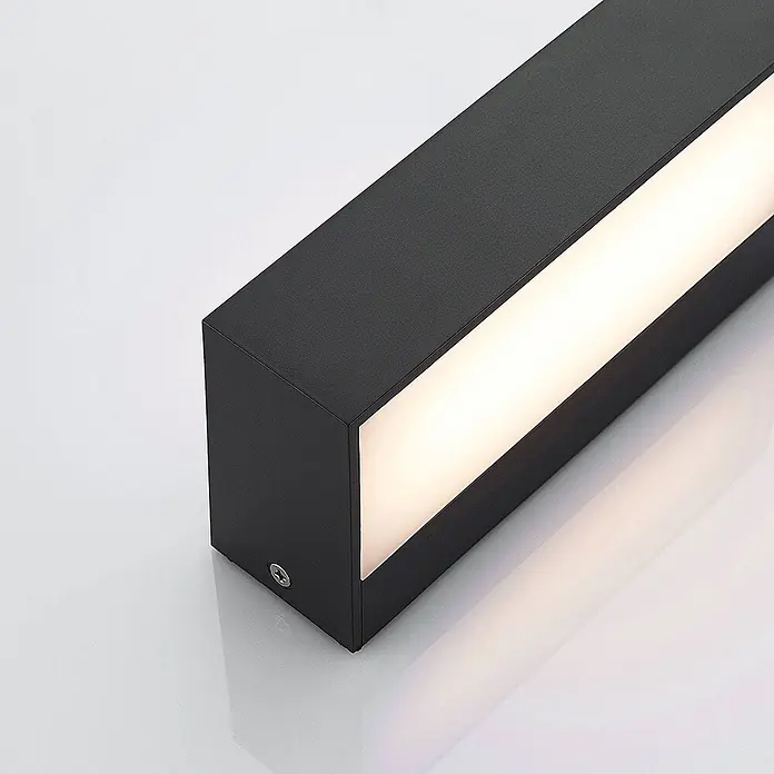 Lindby Außenwandleuchte Nienke - schwarz, schwarz, IP65 - Schwarze rechteckige LED-Leuchte mit einem hellweißen Lichtstreifen an einer Seite und einer silbernen Befestigungsschraube.