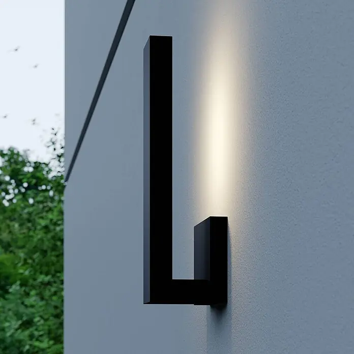 Lindby Außenwandleuchte Isadore - schwarz, schwarz, IP44 - Schwarze L-förmige Außenwandleuchte, die eine strukturierte Wand beleuchtet.
