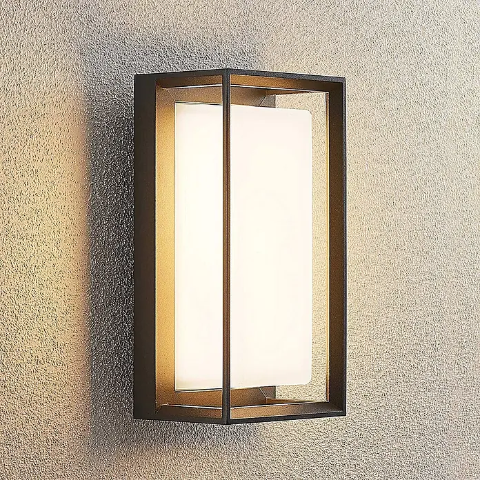 Arcchio Außenwandleuchte Ismera - schwarz, schwarz, IP65 - Moderne Außenwandleuchte mit dunklem Rechteckrahmen und weißer Diffusorplatte, an strukturierter Wand montiert.