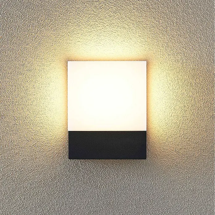 Lindby Außenwandleuchte Vanira - schwarz, IP54 - Quadratische Wandleuchte, oben weiß, unten schwarz, strahlt warmes Licht auf eine strukturierte Wand.