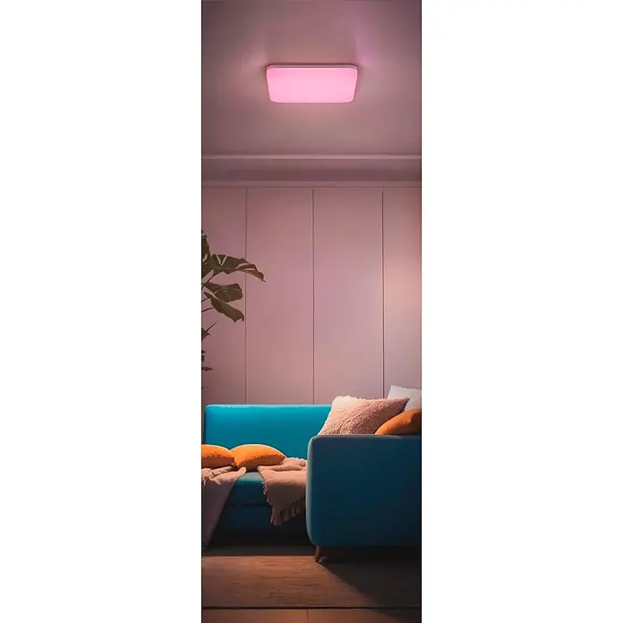 Hama LED-Deckenleuchte Matter WLAN RGBW - L x B x H: 22 x 22 x 5 cm - Eine rechteckige LED-Deckenleuchte spendet leuchtend pinkes Licht und erhellt ein modernes Wohnzimmer mit blauem Sofa.