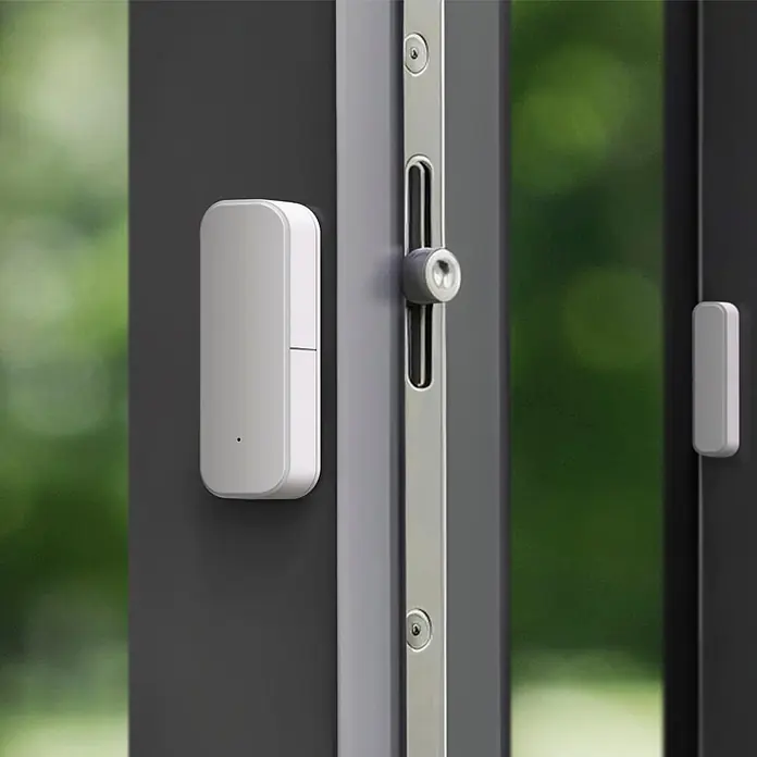 Hama Funk-Fensterkontakt 00176663 für Türen Fenster Garagen Zigbee magnetisch - Weiß - Weißer Smart-Home-Sensor (zwei Teile) an einem dunklen Tür- oder Fensterrahmen montiert.