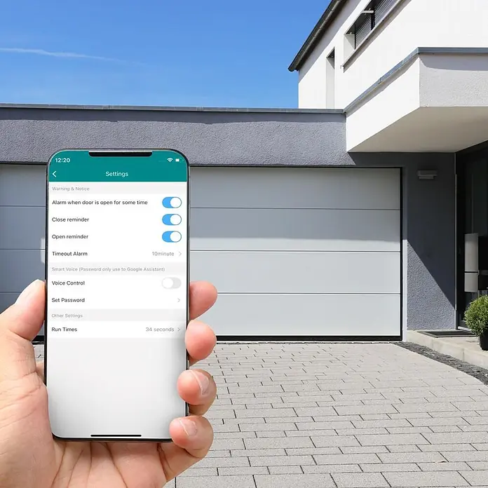 Hama Smartphone-Garagentoröffner 00176680 WLAN mit Sensor Steuerung per App/Sprachbefehl - Schwarz - Eine Hand hält ein Smartphone mit einer Smart-Home-App zur Steuerung eines modernen weißen Garagentors.