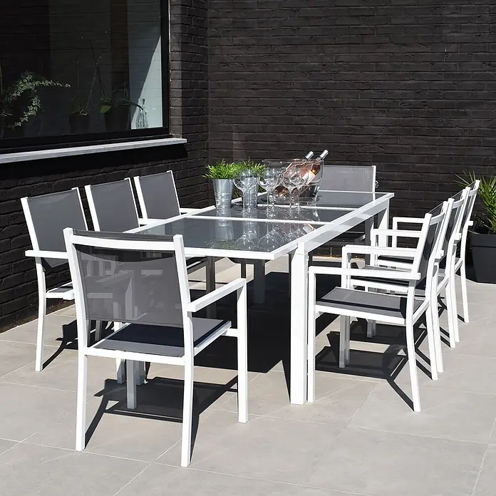 Happy Garden Gartentisch-Set FIRENZE - Gesamtumfang: 9 -tlg., Aluminium - Outdoor-Essgruppe: weißer Aluminiumtisch mit grauer Glasplatte und acht weiß gerahmte Stühle mit grauem Netzstoff auf einer Terrasse.