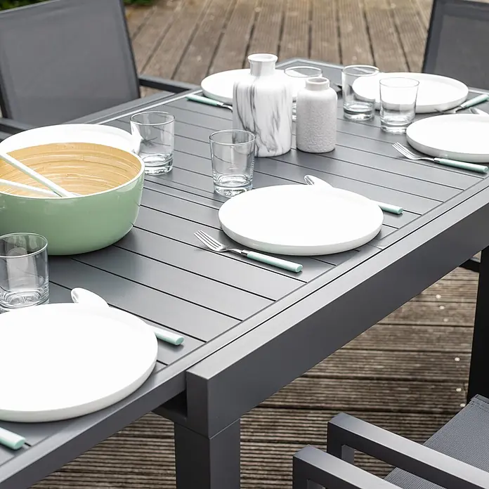 Happy Garden Gartentisch-Set VENEZIA - Gesamtumfang: 9 -tlg., Aluminium - Anthrazitfarbener Outdoor-Esstisch mit weißem Geschirr, mintgrünem Besteck und einer hellgrünen Servierschale, auf Holzterrasse.