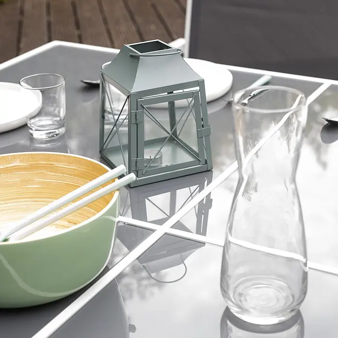 Happy Garden Gartentisch-Set CAGLIARI - Gesamtumfang: 9 -tlg., Aluminium - Ein Außentisch gedeckt mit einer mintgrünen Bambusschale, weißen Stäbchen, einer grauen Laterne und einer Glaskaraffe.