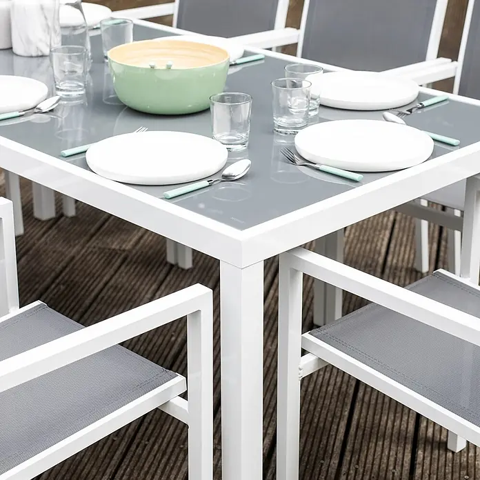 Happy Garden Gartentisch-Set BARI - Gesamtumfang: 9 -tlg., Aluminium - Moderner Outdoor-Esstisch mit weißem Gestell und grauer Platte, dazu graue Netzstühle, auf einer Holzterrasse gedeckt.