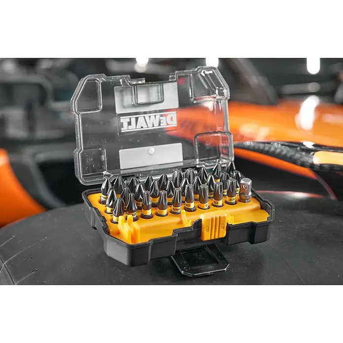DeWalt Set de puntas McLaren - 32 pzs. - Juego de puntas DeWalt con brocas negras y amarillas en estuche transparente y negro, sobre un neumático con fondo naranja.