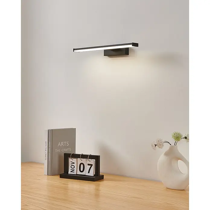 Eglo LED-Spiegelleuchte Galenzana-E - 7,4 W, L x B x H: 12 x 40 x 4 cm, Schwarz, Neutralweiß - Schwarze lineare LED-Bilderleuchte an der Wand, beleuchtet einen Schreibtisch mit Dekoration.