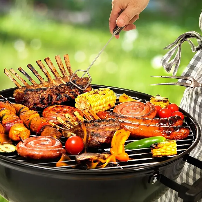 ECD Germany Grillrost Grillplatte 54,5 cm Rund für Gasgrill Holzkohlegrill Feuerstelle - L x B: 54,5 x 54,5 cm, Edelstahl, Holz - Ein schwarzer Holzkohlegrill ist mit verschiedenen gegrillten Fleisch- und Gemüsesorten beladen und wird von einer Hand mit einem Grillwerkzeug bedient.