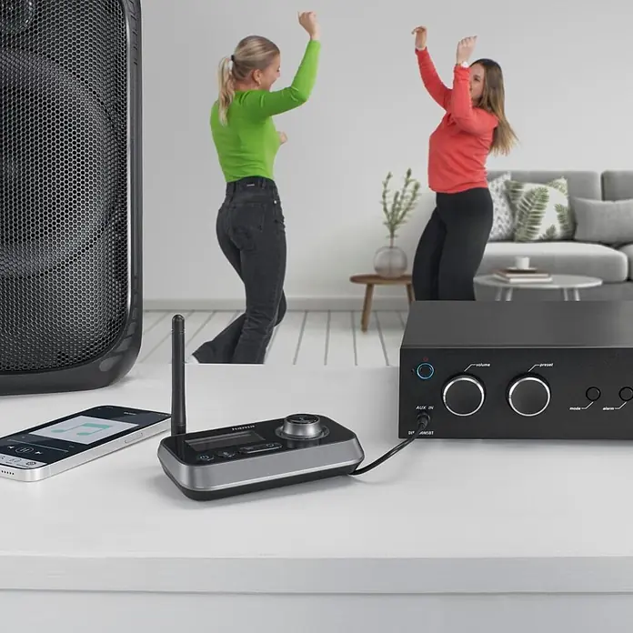 Hama Radio 00205322 "Link.it duo" Sender u. Empfänger Bluetooth nachrüsten - Schwarz - Schwarz/silbernes Audiosystem: Empfänger, Verstärker, Smartphone, Lautsprecher auf weißem Tisch, spielt Musik zum Tanzen.