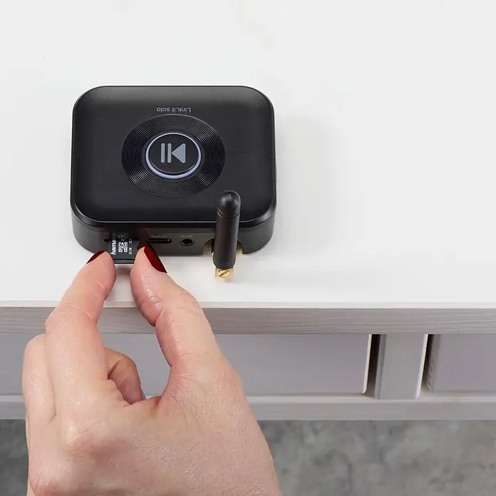 Hama Adapter 00205321 "Link.it solo" Empfänger Bluetooth nachrüsten an HiFi - Schwarz - Schwarzer Link.it solo Audio-Empfänger/Sender, eine Hand steckt eine microSD-Karte in den Seitenschlitz.