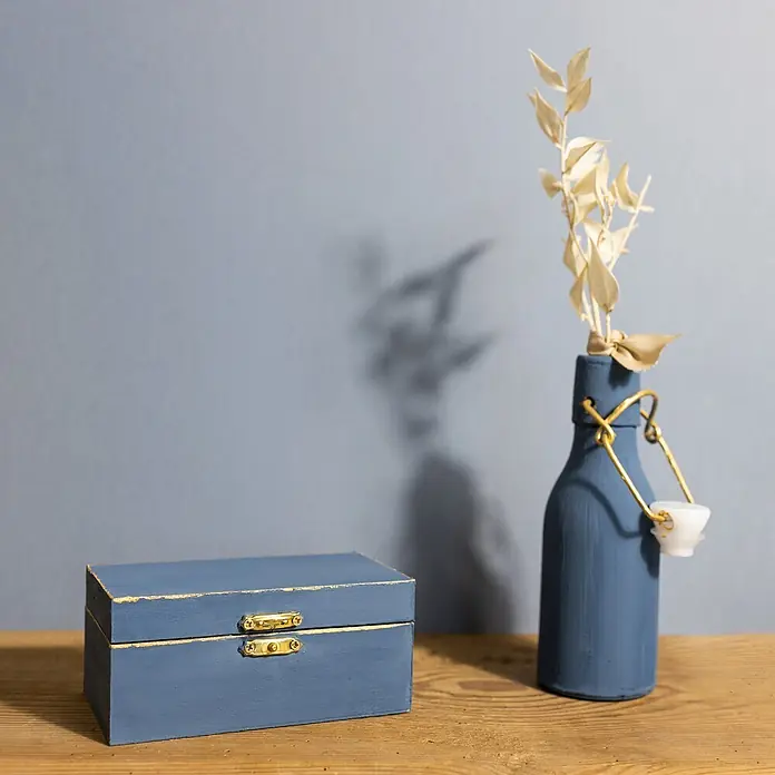 Creative Deco Speziallack Kreidefarbe für Möbel Jeans Blau - Blau, Matt, 1 l, Wasserbasiert - Eine blaue dekorative Holzschachtel neben einer blauen Flasche mit Trockenpflanzen auf einer Holzoberfläche.