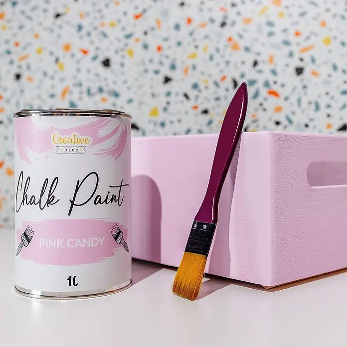 Creative Deco Speziallack Kreidefarbe für Möbel Rosa - Rosa, Matt, 1 l, Wasserbasiert - Rosafarbene Kreidefarbe-Dose und Pinsel neben einer bemalten Holzkiste auf Terrazzo-Hintergrund.