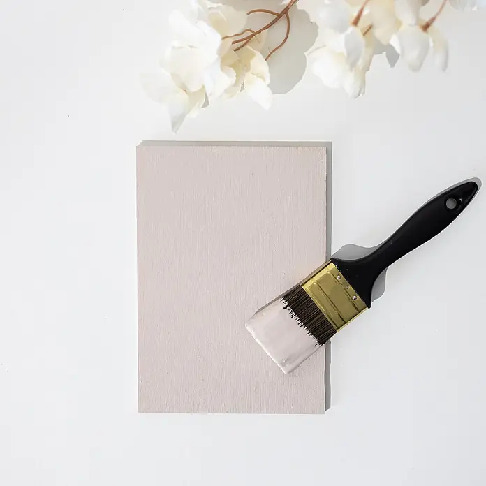 Creative Deco Speziallack Kreidefarbe für Möbel Puderbeige - Beige, Matt, 1 l, Wasserbasiert - Pinsel mit hellrosa Farbe auf den Borsten, liegt auf einer strukturierten hellbeigen Farbprobe.