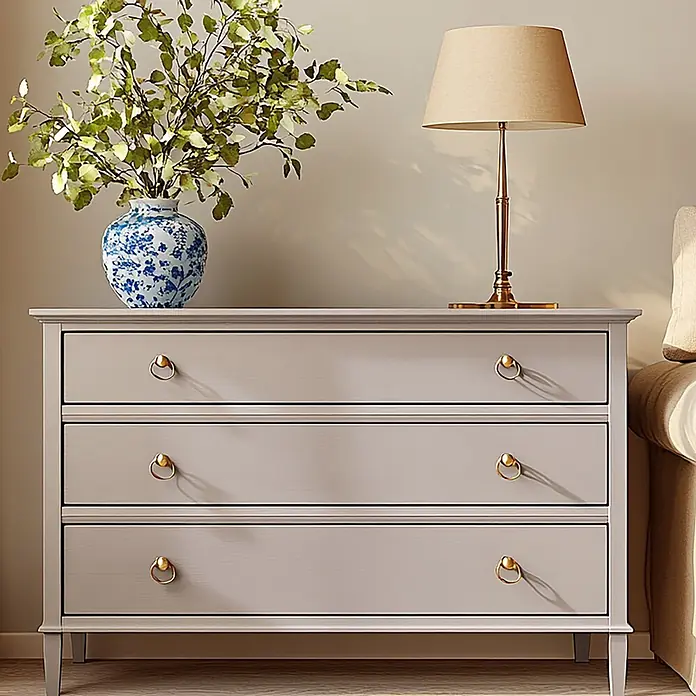 Creative Deco Speziallack Kreidefarbe für Möbel Puderbeige - Beige, Matt, 1 l, Wasserbasiert - Hellgraue Kommode mit goldenen Ringgriffen, darauf eine Vase mit Grün und eine Lampe, neben einem Sofa.