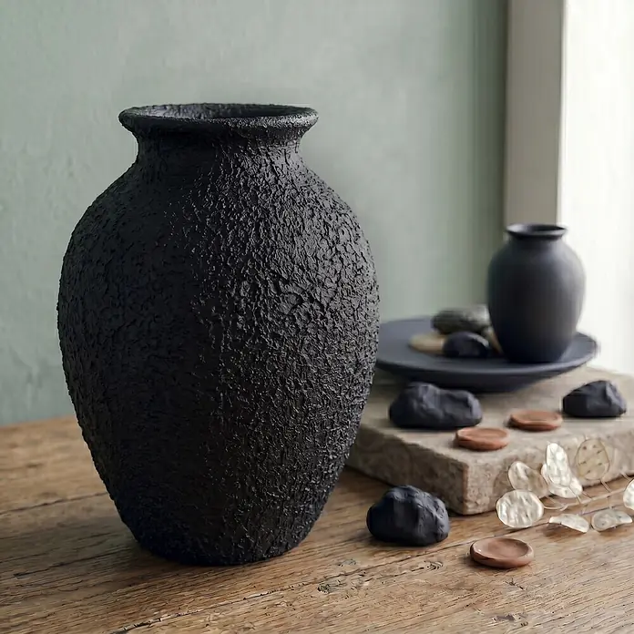 Creative Deco Speziallack Strukturpaste Grobkörnig 2 kg Schwarz - Schwarz, Sonstiges, 1 l, Sonstiges - Große schwarze strukturierte Vase auf einem Holztisch, neben Dekorationssteinen und einer kleineren dunklen Vase, in einem sanft beleuchteten Innenraum.