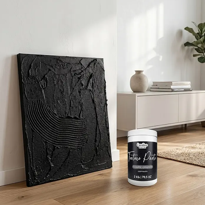 Creative Deco Speziallack Strukturpaste Grobkörnig 2 kg Schwarz - Schwarz, Sonstiges, 1 l, Sonstiges - Weißer Behälter mit Creative Deco Tiefschwarz grobkörniger Strukturpaste auf Holzboden neben schwarzem Texturkunstwerk.