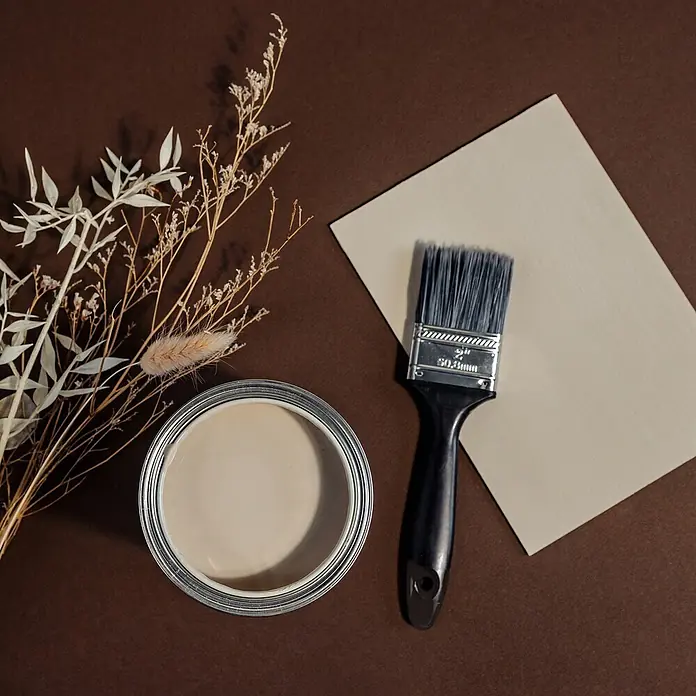 Creative Deco Speziallack Kreidefarbe für Möbel Sandbeige - Beige, Matt, 1 l, Wasserbasiert - Eine offene Dose hellbeiger Farbe, ein Pinsel und ein Farbmuster, arrangiert mit Trockenblumen auf braunem Untergrund.