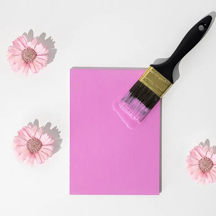 Creative Deco Speziallack Kreidefarbe für Möbel Fuchsia - Rosa, Matt, 1 l, Wasserbasiert - Pinsel mit rosa Farbe auf einer rosa Platte, umgeben von rosa Deko-Blumen.