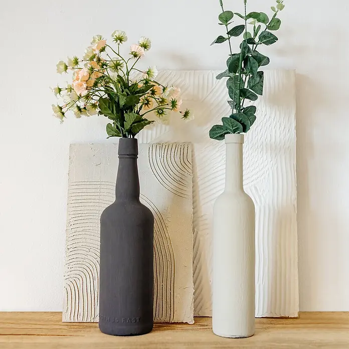 Creative Deco Speziallack Kreidefarbe für Möbel Kräutergrün - Grün, Matt, 1 l, Wasserbasiert - Zwei dekorative flaschenförmige Vasen, eine dunkelgrau mit hellen Blumen, eine cremefarben mit grünem Eukalyptus, auf Holzoberfläche.
