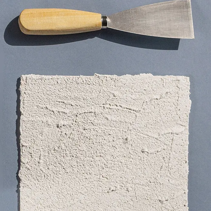 Creative Deco Speziallack Strukturpaste Grobkörnig 1 kg Weiß - Weiß, Sonstiges, Sonstiges - Metallspachtel mit Holzgriff neben einer strukturierten weißen Putzprobe.