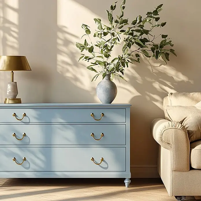 Creative Deco Speziallack Kreidefarbe für Möbel Hellblau - Blau, Matt, 1 l, Wasserbasiert - Hellblaue Kommode mit Goldgriffen, darauf eine Lampe und Vase, neben einem cremefarbenen Sofa.