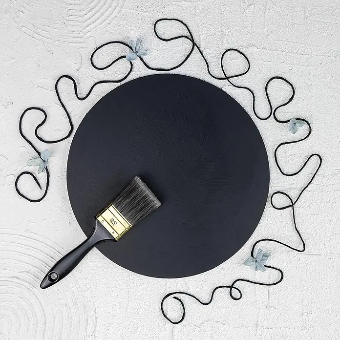 Creative Deco Speziallack Kreidefarbe für Möbel Schwarz - Schwarz, Matt, 1 l, Wasserbasiert - Schwarze runde Leinwand mit Pinsel, umgeben von schwarzer Wolle und kleinen blauen Trockenblumen.