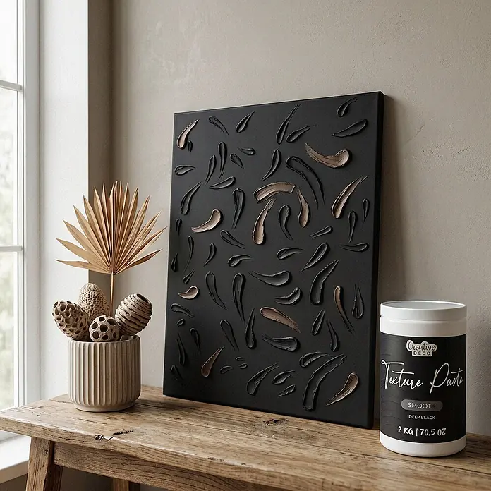 Creative Deco Speziallack Strukturpaste Glatt 2 kg Schwarz - Schwarz, Sonstiges, 1 l, Sonstiges - Eine Dose Creative Deco Deep Black Smooth Strukturpaste steht neben einem strukturierten Kunstwerk auf einem Holztisch am Fenster.
