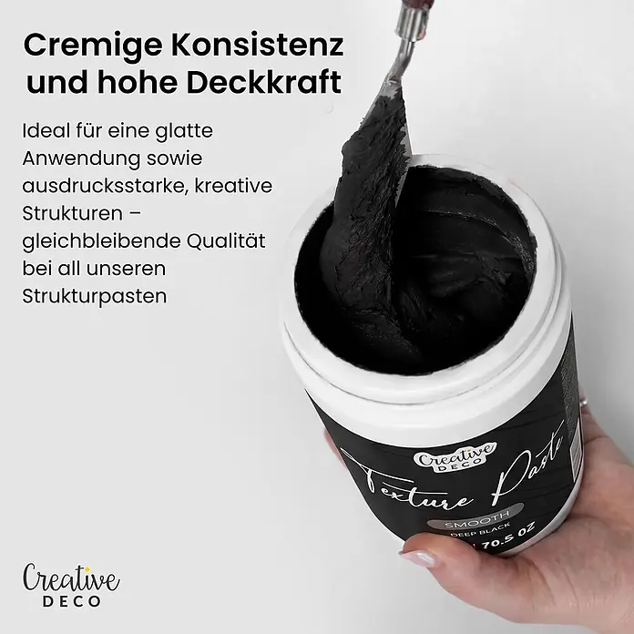Creative Deco Speziallack Strukturpaste Glatt 2 kg Schwarz - Schwarz, Sonstiges, 1 l, Sonstiges - Eine Hand hält einen geöffneten Tiegel schwarzer Strukturpaste, in die ein Spachtel taucht.