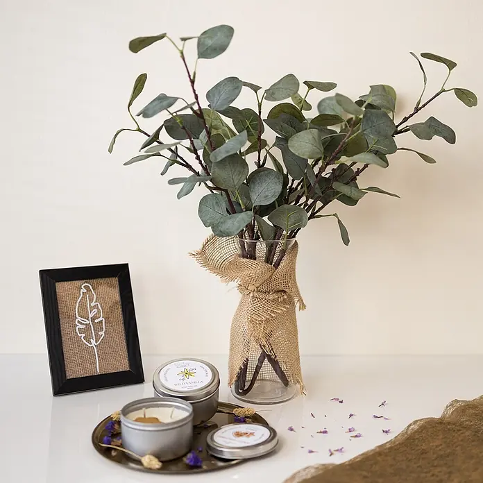Creative Deco Bastelband Juteband 20cm x 10m - Braun - Drei Duftkerzen in Silbertöpfen auf einem Tablett, neben einer mit Jute umwickelten Vase mit Eukalyptus und einem gerahmten Federbild.