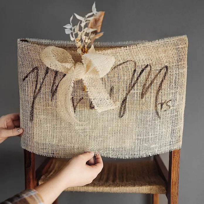 Creative Deco Bastelband Juteband Weiß 30cm x 10m - Weiß, 10 m - Sackleinen-Stuhlhussen mit 'Mr. & Mrs.'-Aufschrift, Juteschleife und Trockenblumen, auf einem Holzstuhl angepasst.