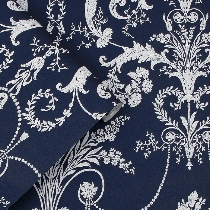 Laura Ashley Vliestapete Vliestapete Josette Damast - Dunkelblau, Ornament, 10 x 0,52 m - Dunkelblaue Tapete mit einem kunstvollen weißen Blumen- und Rankenmuster, teilweise abgerollt.