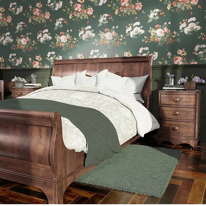 Laura Ashley Vliestapete Rosemore - Dunkelgrün, Floral, 1.000 x 52 cm - Ein dunkelbraunes Schlittenbett aus Holz mit weißer Bettwäsche, grünem Überwurf und passenden Nachttischen in einem Schlafzimmer mit Blumenmuster.