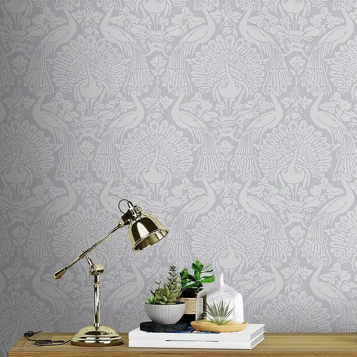 Laura Ashley Vliestapete Pfauendamast - Grau, Tieroptik, 1.000 x 52 cm - Hellgraue Tapete mit weißem Pfauen- und Blumenmuster, an einer Wand hinter einem Schreibtisch mit Dekoration.