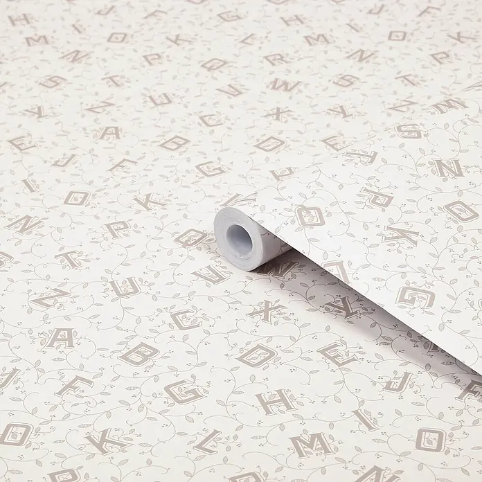 Laura Ashley Vliestapete Alphabet - Braun/Grau, Floral, 1.000 x 52 cm - Hellbeigefarbene Tapetenrolle mit dekorativem Alphabet- und Rankenmuster, teilweise abgerollt.