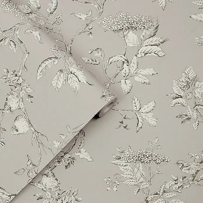 Laura Ashley Vliestapete Elderwood - Grau, Floral, 1.000 x 52 cm - Teilweise ausgerollte graue Tapete mit einem detailreichen weißen und dunkelgrauen Pflanzenmuster aus Ästen, Blättern, Beeren und Vögeln.
