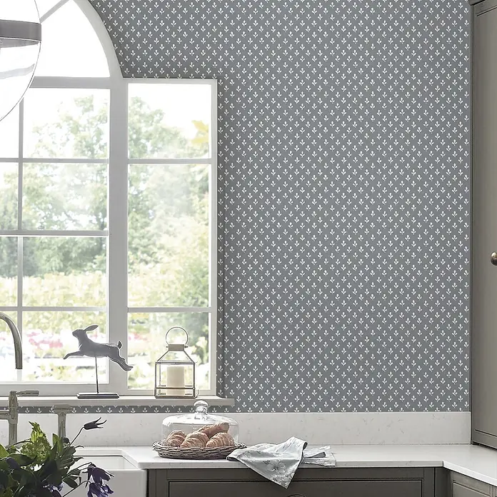 Laura Ashley Vliestapete Trefoil - Grau, Ornament, 1.000 x 52 cm - Graue gemusterte Tapete mit weißen Blattmotiven an einer Küchenwand.