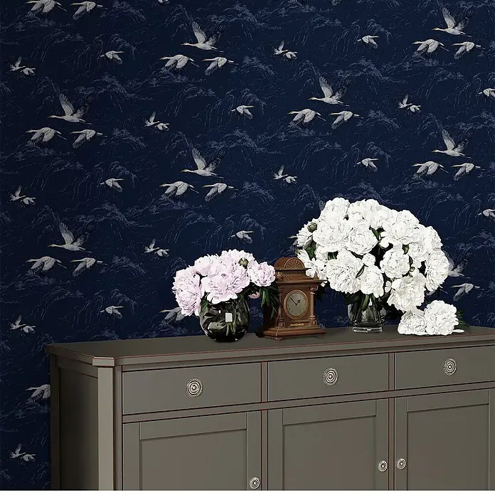 Laura Ashley Vliestapete Animalia - Dunkelblau, Tieroptik, 1.000 x 52 cm - Dunkelgraues Sideboard mit Schubladen und Schränken, mit Blumenväschen und antiker Uhr.
