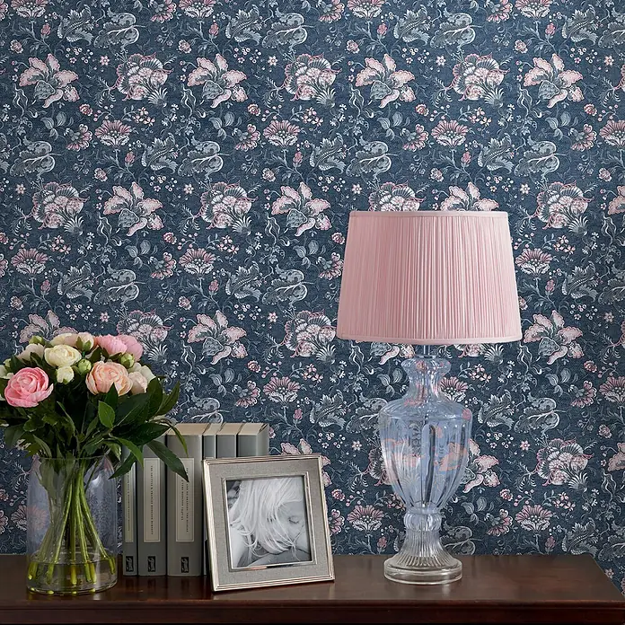 Laura Ashley Vliestapete Vliestapete Portia - Blau, Floral, 10 x 0,52 m - Dunkelblaue Blumentapete mit rosa und grauen Blumenmustern an einer Wand hinter einem Konsolentisch.