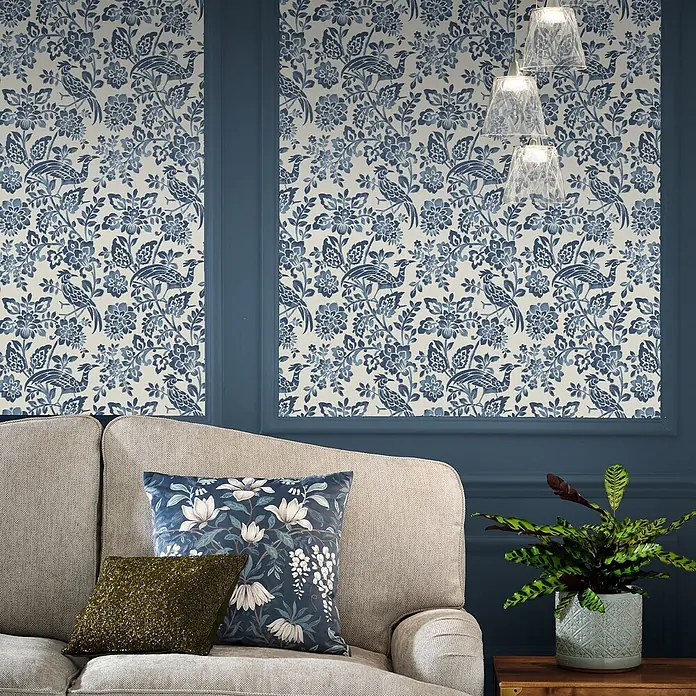 Laura Ashley Vliestapete Vliestapete Adain Palace Blumen - Blau, Floral, 10 x 0,52 m - Blau-weiß gemusterte Tapete mit Blumen und Vögeln an Wandpaneelen in einem Wohnzimmer.