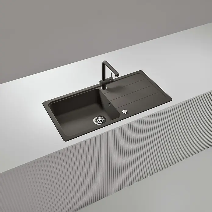 Schock Einbauspüle Formhaus - 100 x 50 cm, Asphalt, Quarzkomposit - Dunkelgraue Küchenspüle mit integrierter Abtropffläche und passender dunkelgrauer Armatur, in eine weiße Arbeitsplatte eingebaut.