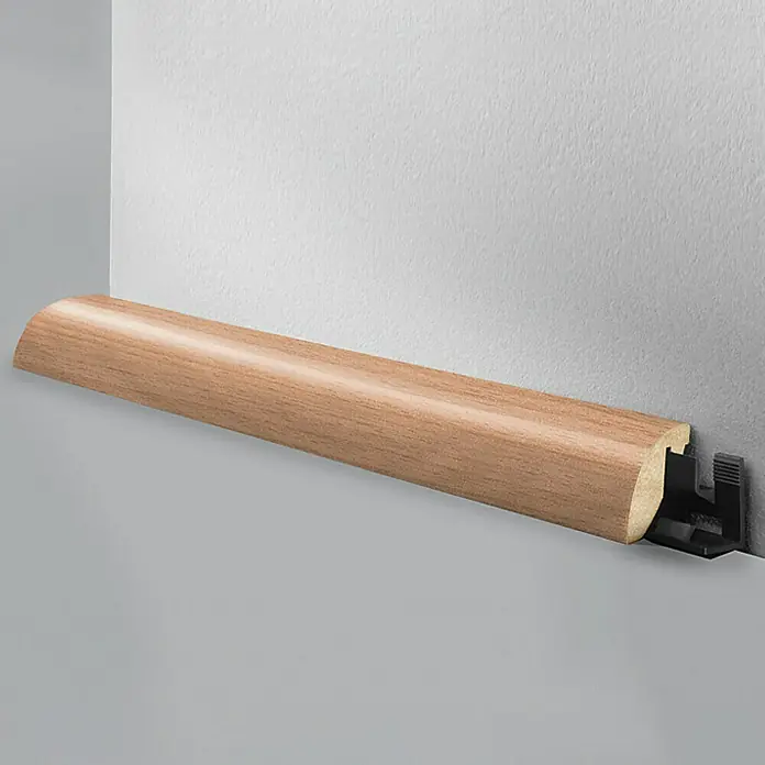 LOGOCLIC Viertelstab Buche Hell - 260 cm x 23 mm x 29 mm, MDF - Bild einer Sockelleiste aus Holz mit einem schwarzen Kunststoffbefestigungssystem an einer grauen und weißen Wand.