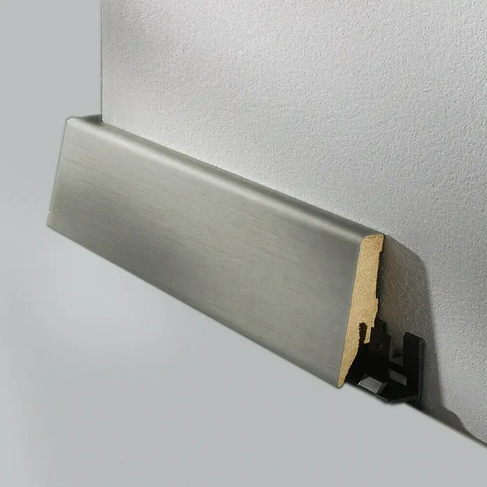 LOGOCLIC Sockelleiste K58 D Champagner - 260 cm x 19 mm x 58 mm, MDF - Das Bild zeigt eine graue Sockelleiste mit Holzprofil und schwarzem Clip-System, die an einer weißen Wand befestigt ist.