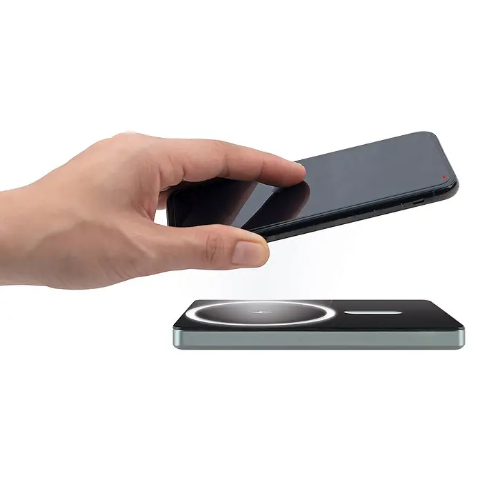 Schwaiger Powerbank magnetisch Wireless - Schwarz - Hand hält schwarzes Smartphone über dunklem kabellosen Ladegerät mit beleuchtetem Ring, das kabelloses Laden zeigt.