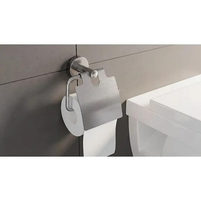 Camargue Paris Toilettenpapierhalter - Edelstahl, Silber - Gebürsteter Edelstahl-Toilettenpapierhalter mit Schutzabdeckung, an der Wand montiert, hält eine Rolle weißes Toilettenpapier neben einer Toilette.